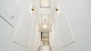 Una escalera con paredes blancas y un candelabro.