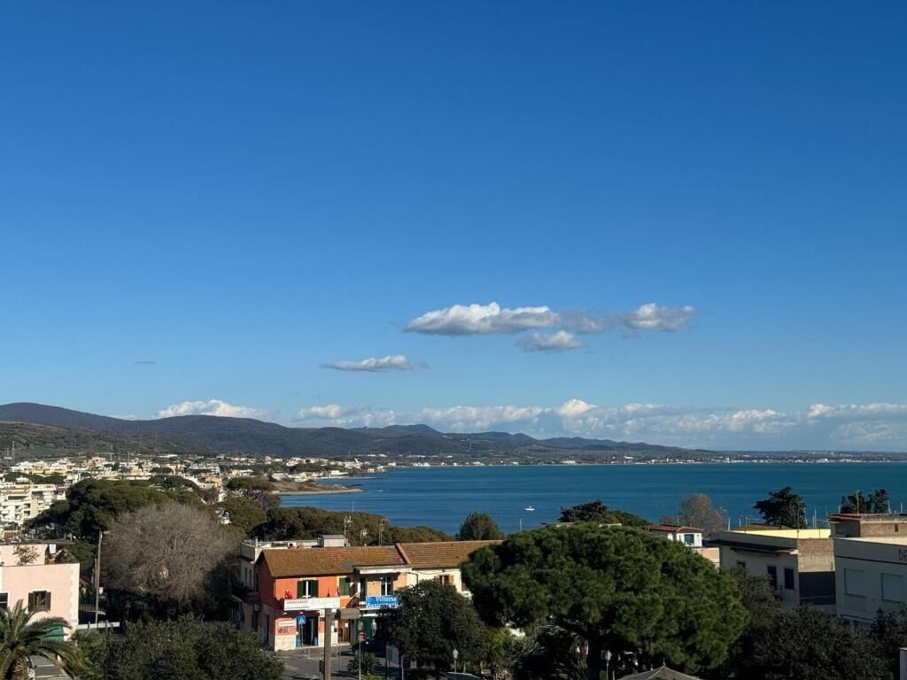 A coastal town with buildings, a clear blue sky, and a view of the sea.