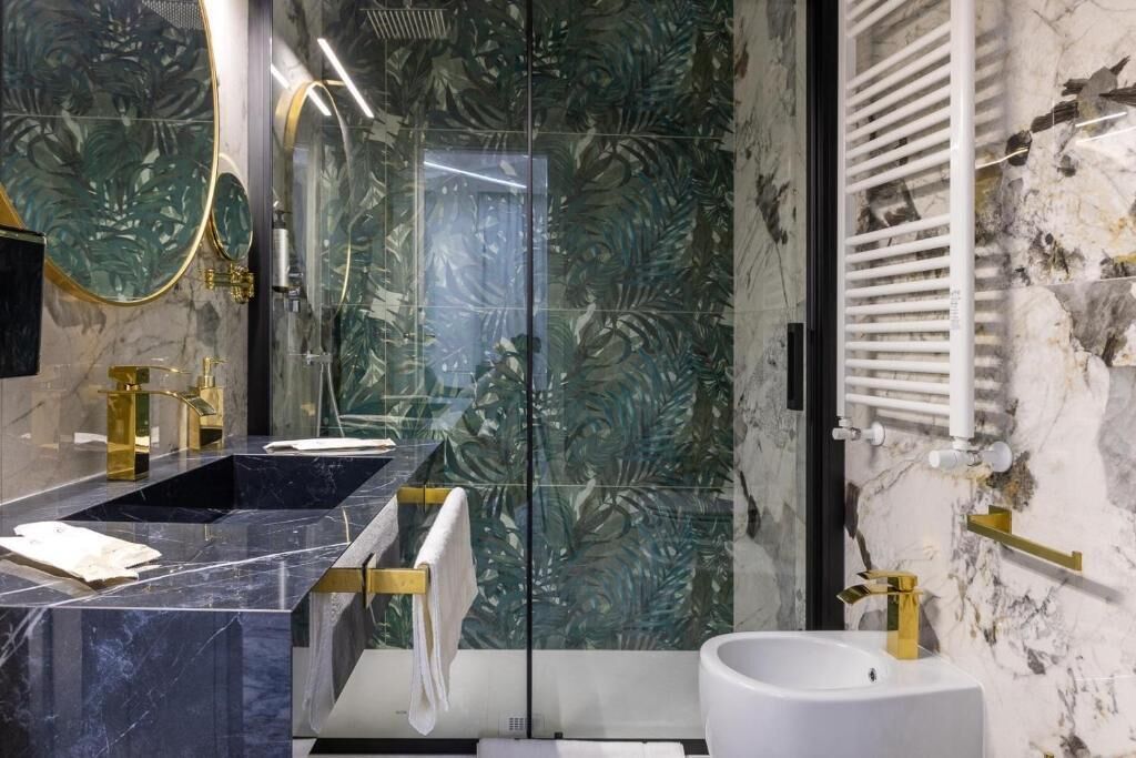 Un bagno moderno con una vanità in marmo, un ampio specchio e cabina doccia in vetro.