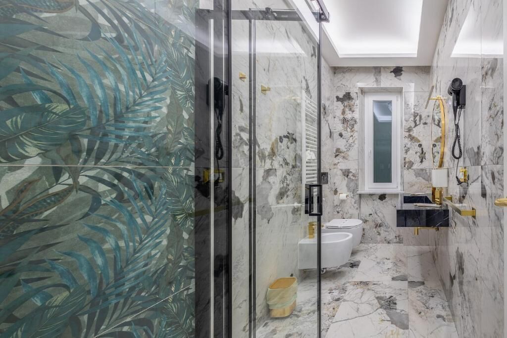 Une salle de bain avec une douche à parois de verre, des toilettes et un lavabo avec un miroir au-dessus.