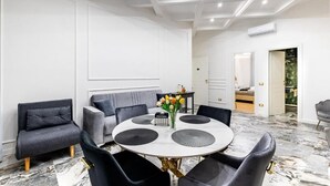 Un comedor moderno con una mesa redonda, sillas negras y un jarrón con flores.