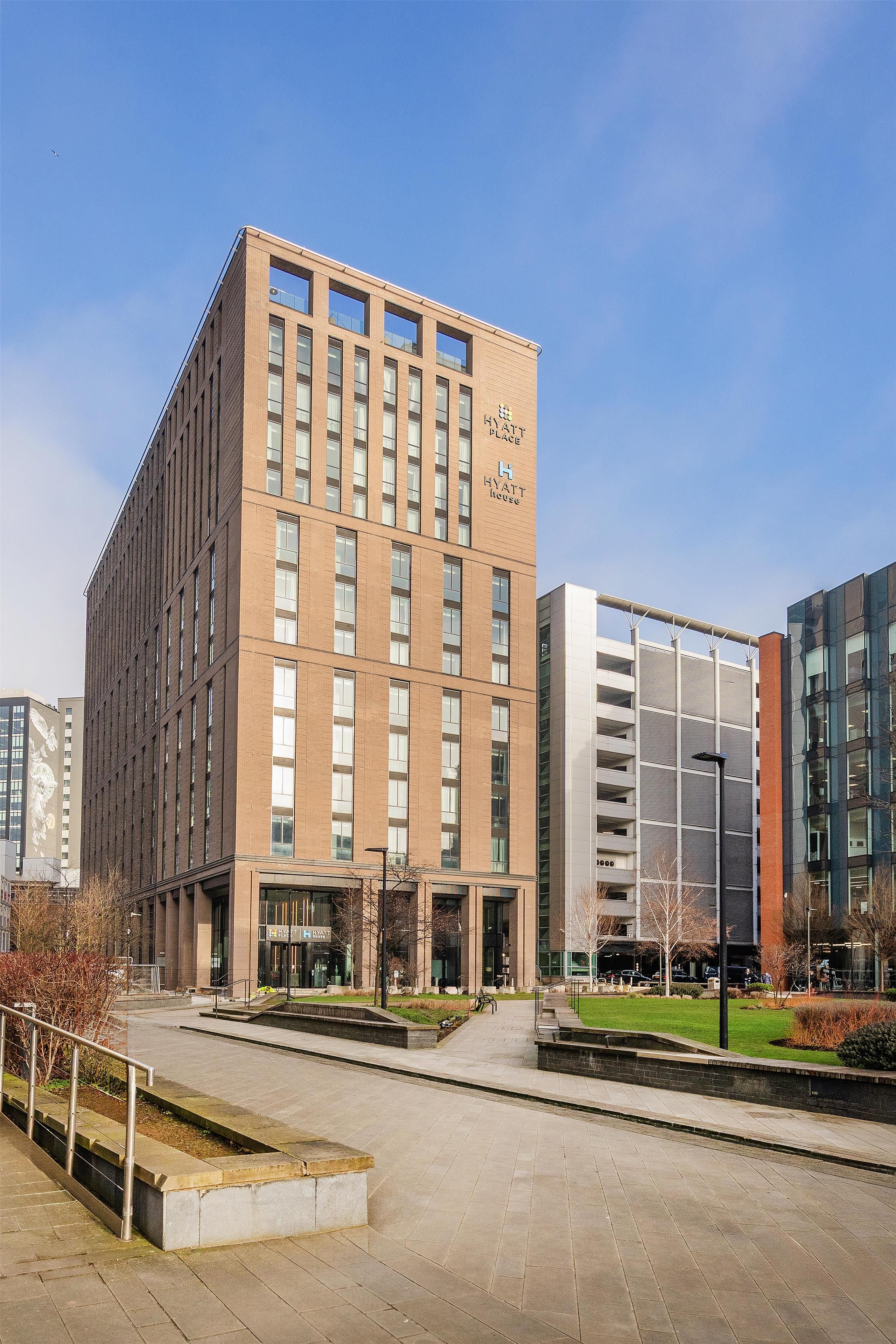 Un edificio moderno con un llamativo letrero de 'Hyatt Place', que presenta fachada de ladrillo y múltiples ventanas.