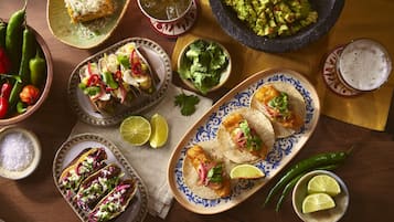 A table with various dishes, including tacos and a bowl of guacamole.
