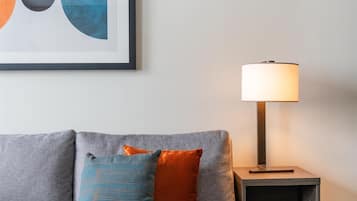 A modern living room with a grey sofa, a blue ottoman, and a floor lamp.