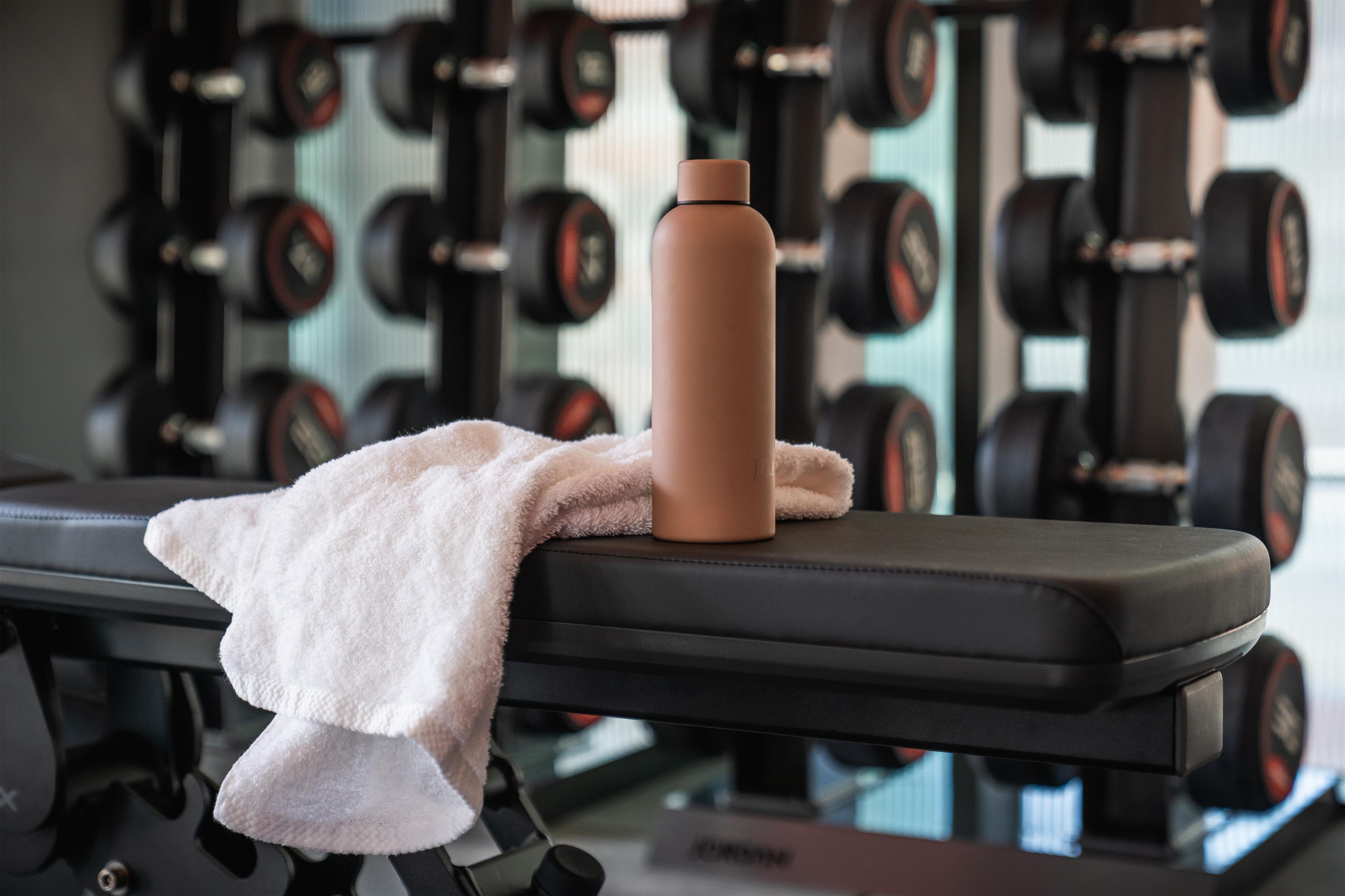 A gym bench with a towel and a water bottle.