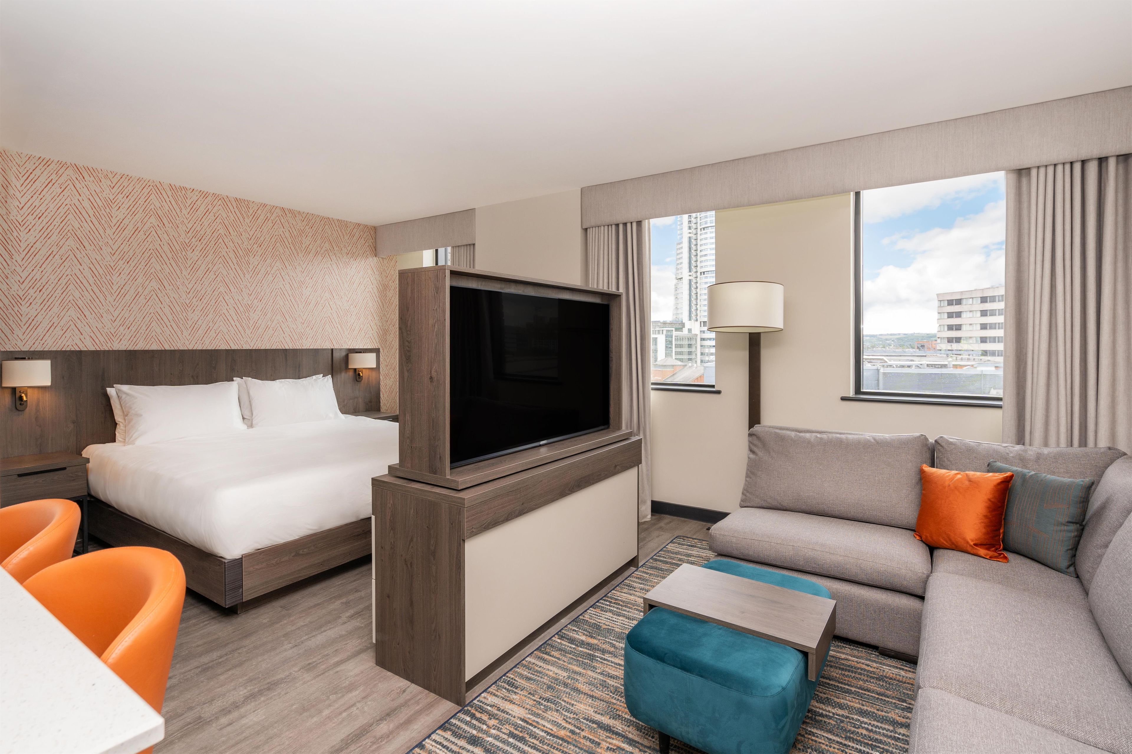 A hotel room with a bed, a TV, a sofa, and a desk.