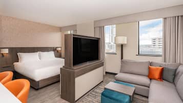 A hotel room with a bed, a TV, a sofa, and a desk.