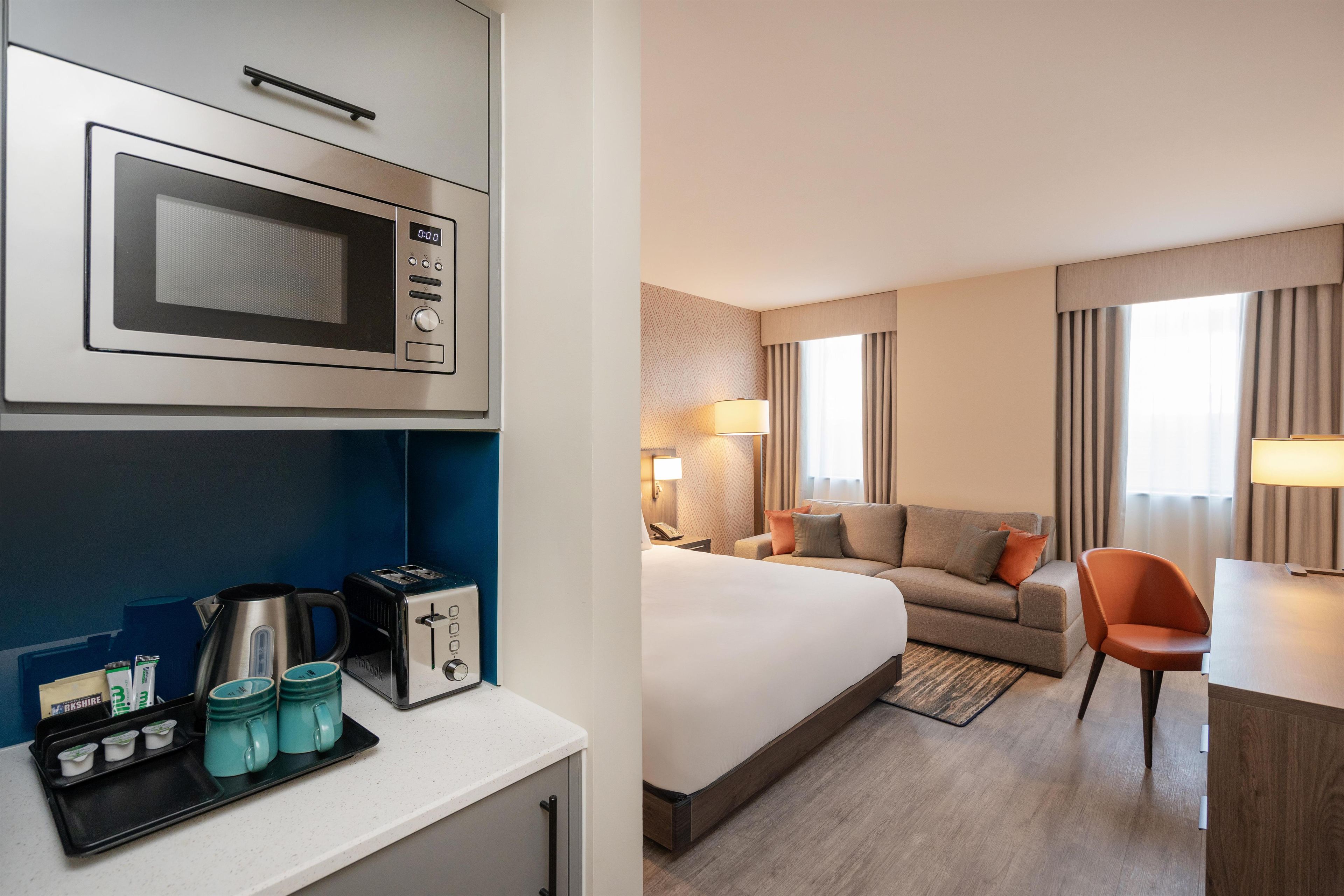 Une chambre d’hôtel équipée d’un lit, d’un canapé, d’un bureau, d’une lampe et d’un four à micro-ondes.