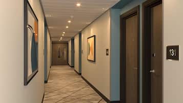 Un corridoio d'albergo con una moquette fantasia, opere d'arte incorniciate alle pareti e porte con i numeri 130 e 131.