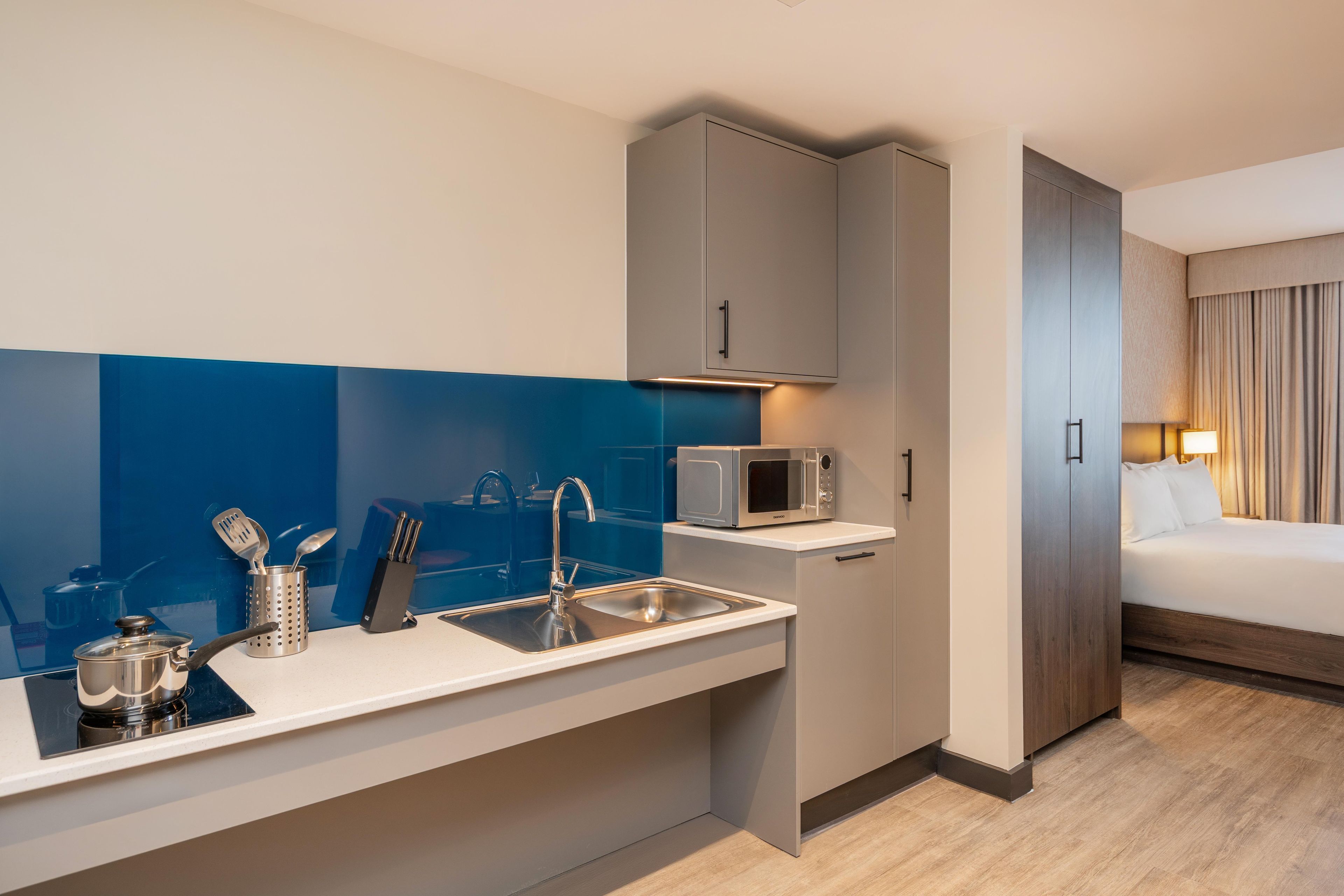 Een kleine hotelkamer met kitchenette, bed en badkamer.