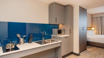 Een kleine hotelkamer met kitchenette, bed en badkamer.