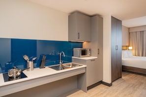 A compact hotel room with a kitchenette, a bed, and a bathroom. - Hyatt House Leeds Aparthotel (Leeds)