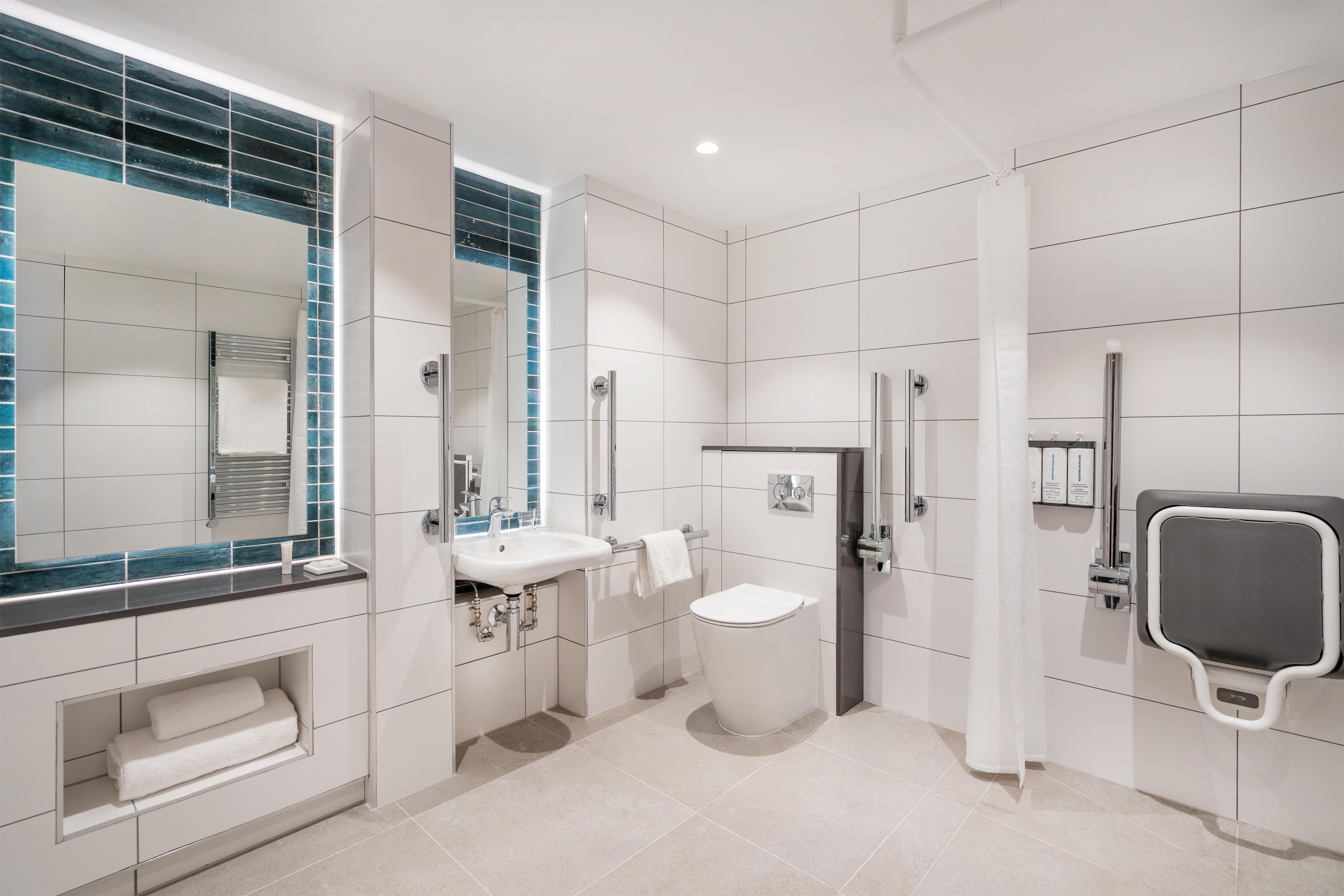 A modern bathroom with a white sink, toilet, and shower area.