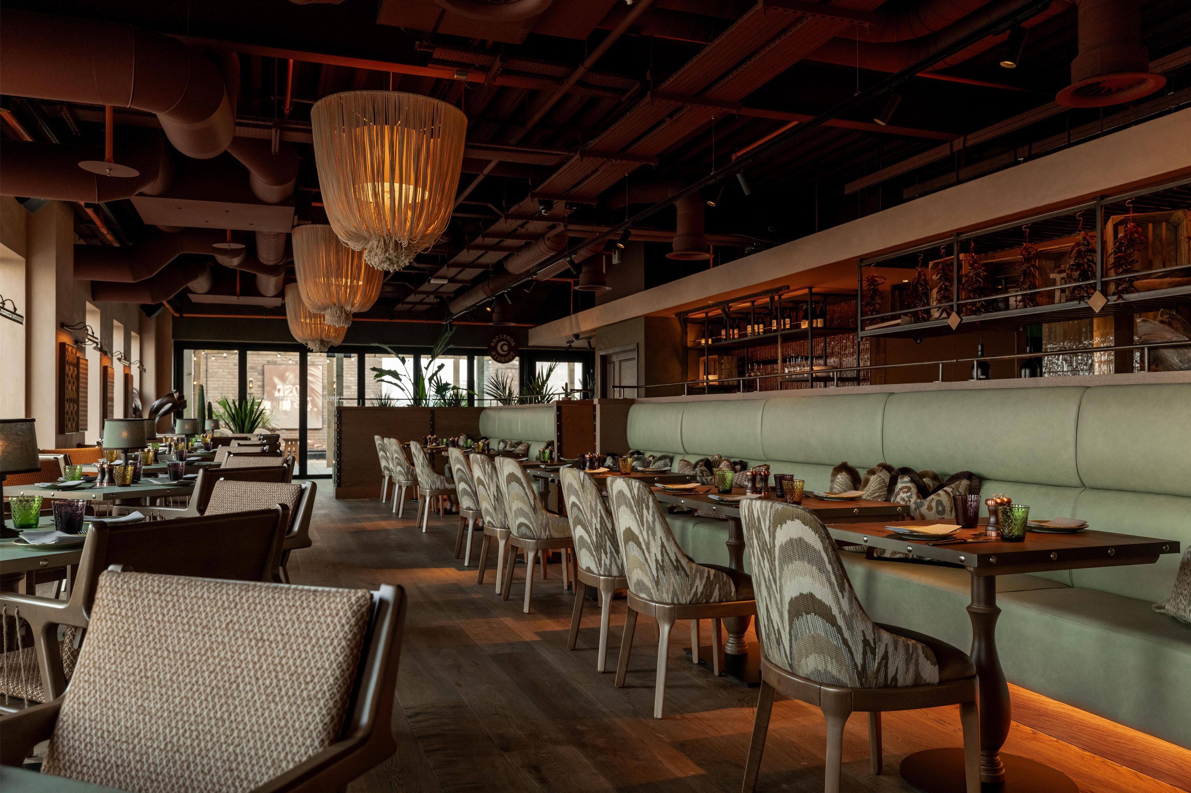 Een restaurant met een lange toonbank, zachte zitplaatsen en hangende lampen.