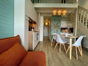 Une cuisine moderne avec des meubles en bois, un coin repas comprenant une table et des chaises, et un escalier menant Ă lâĂ©tage supĂ©rieur.