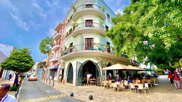 A multi-story hotel with a curved facade, outdoor seating area, and a visible entrance. - Casa Grande (Santo Domingo)