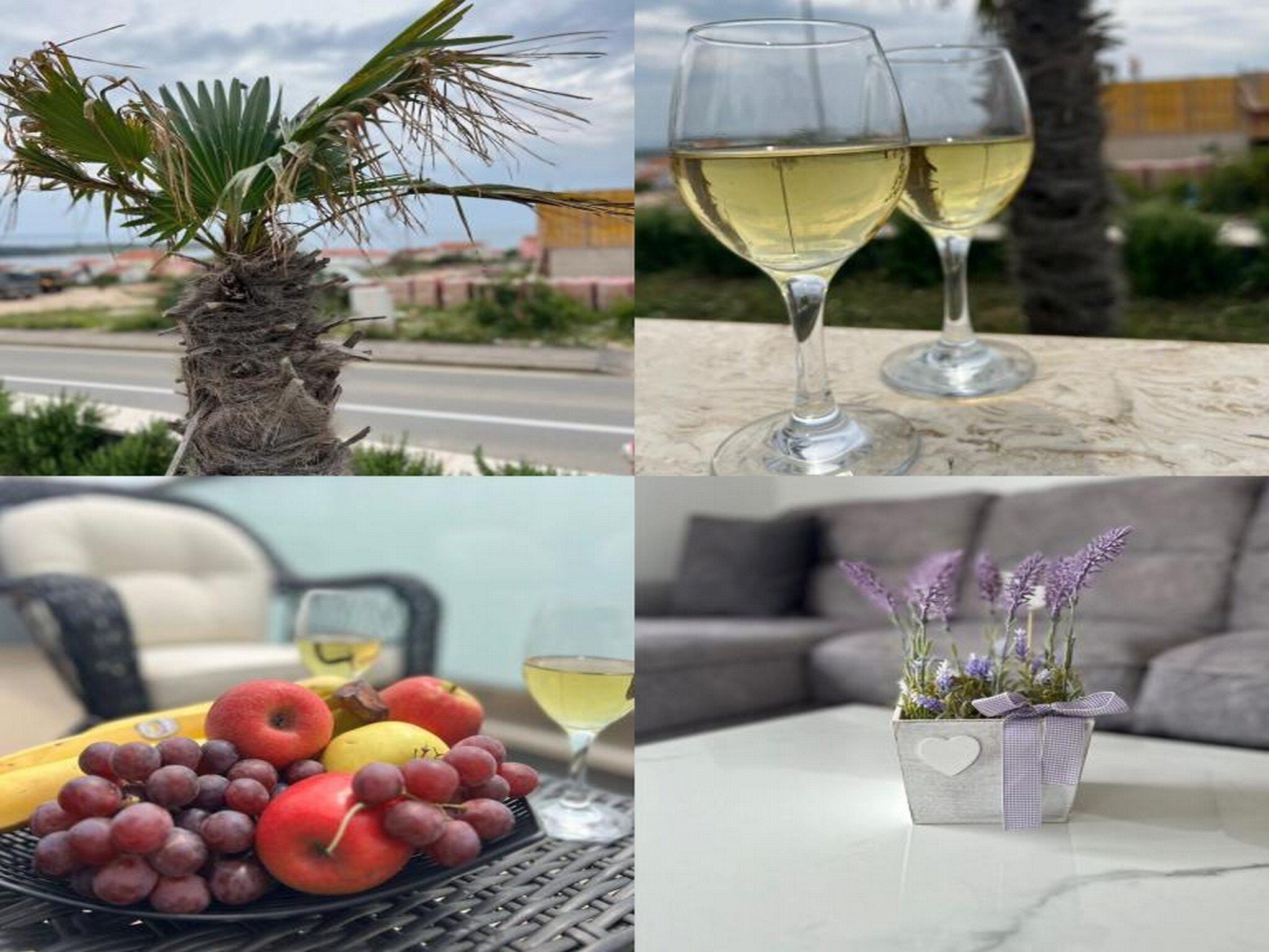 A palm tree, two glasses of white wine, a fruit platter, and a decorative vase with purple flowers.