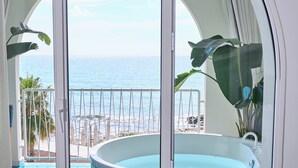A balcony with a view of the ocean, a hot tub, and a tiled floor. - CALEA Boutique Hotel (Bacoli)