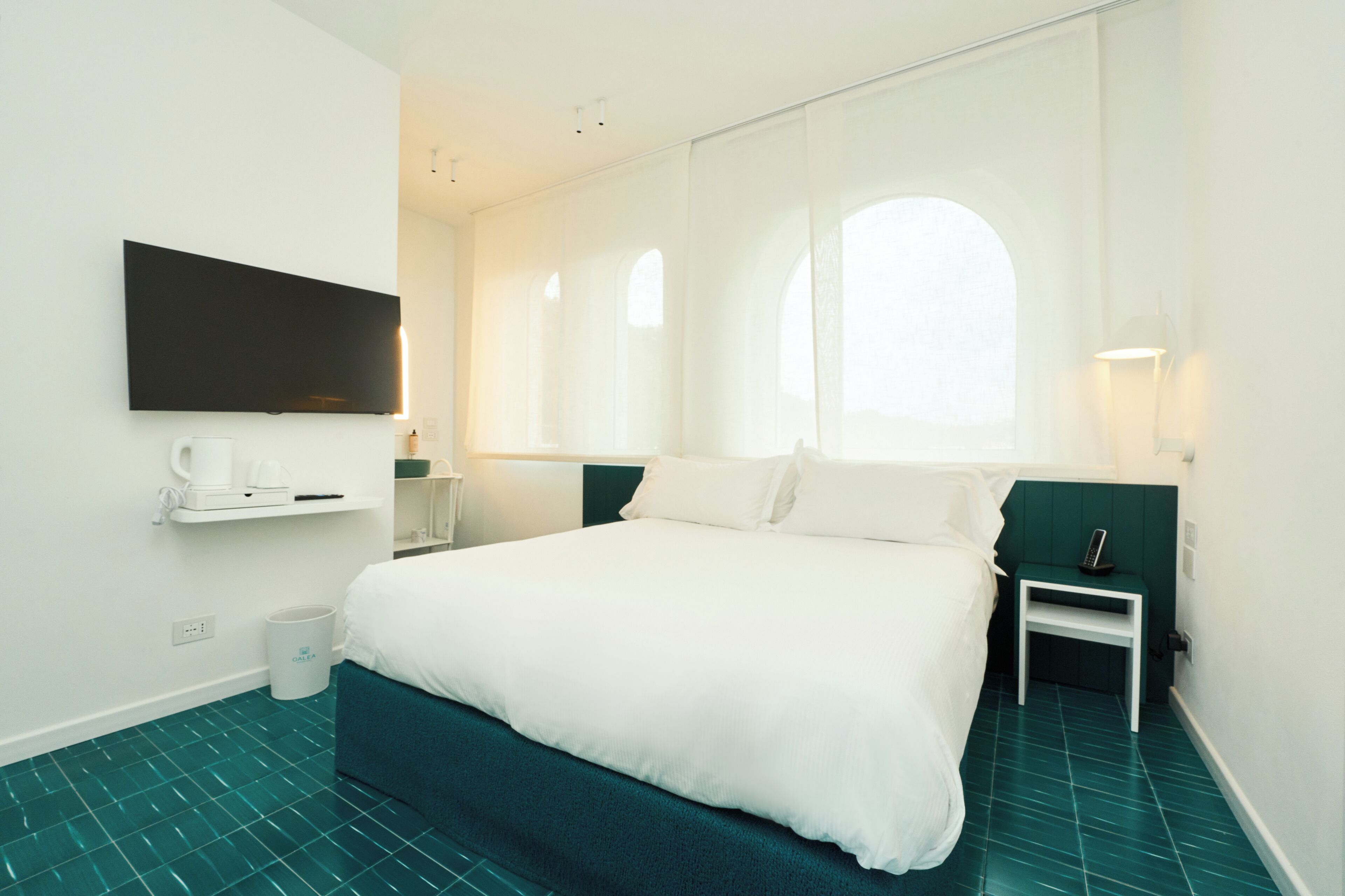 Een moderne hotelkamer met een groot bed, een flatscreen-tv aan de wand, een klein nachtkastje met een lamp, en een raam met uitzicht.