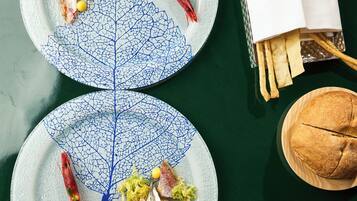 Two plates with food and a bread roll on a table.
