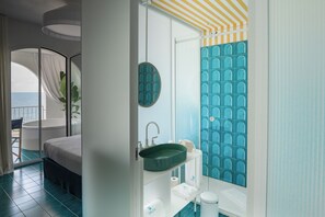 Enjoy a serene sea view from the comfort of this stylish room, featuring a large bed, a green sink, and a spacious bathroom.