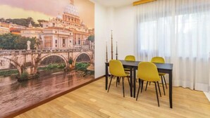 A dining area with a mural of a bridge and buildings, wooden flooring, and yellow chairs. - Spacious 4 bedroom Apartment near St. Peter's Basilica (Roma)