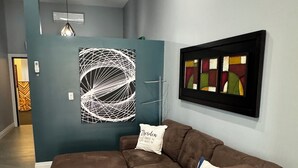 Un salon moderne avec un canapé d’angle, une table basse en verre et des œuvres d’art abstraites accrochées au mur.
