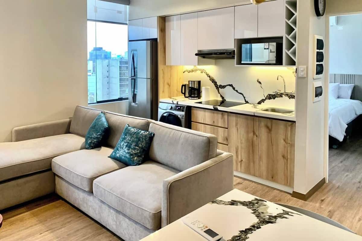Un appartement moderne comprenant un espace de vie, une kitchenette et une chambre.