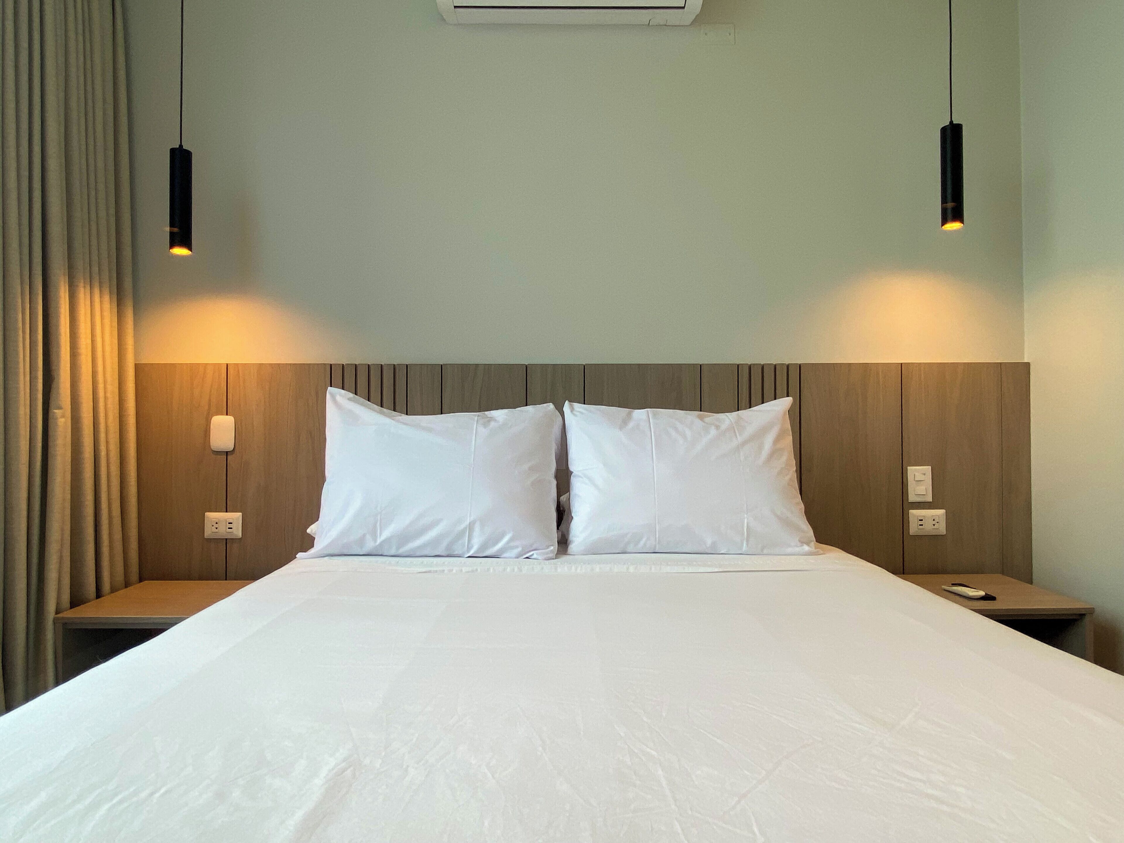 Ein Hotelzimmer mit einem großen Bett, zwei Nachttischen und zwei Pendelleuchten.