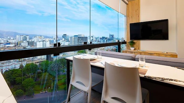 A modern dining area with a city view, a flat-screen TV, and a minimalist design.