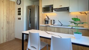 A modern kitchen with stainless steel appliances, a wooden door, and a white dining table with chairs.
