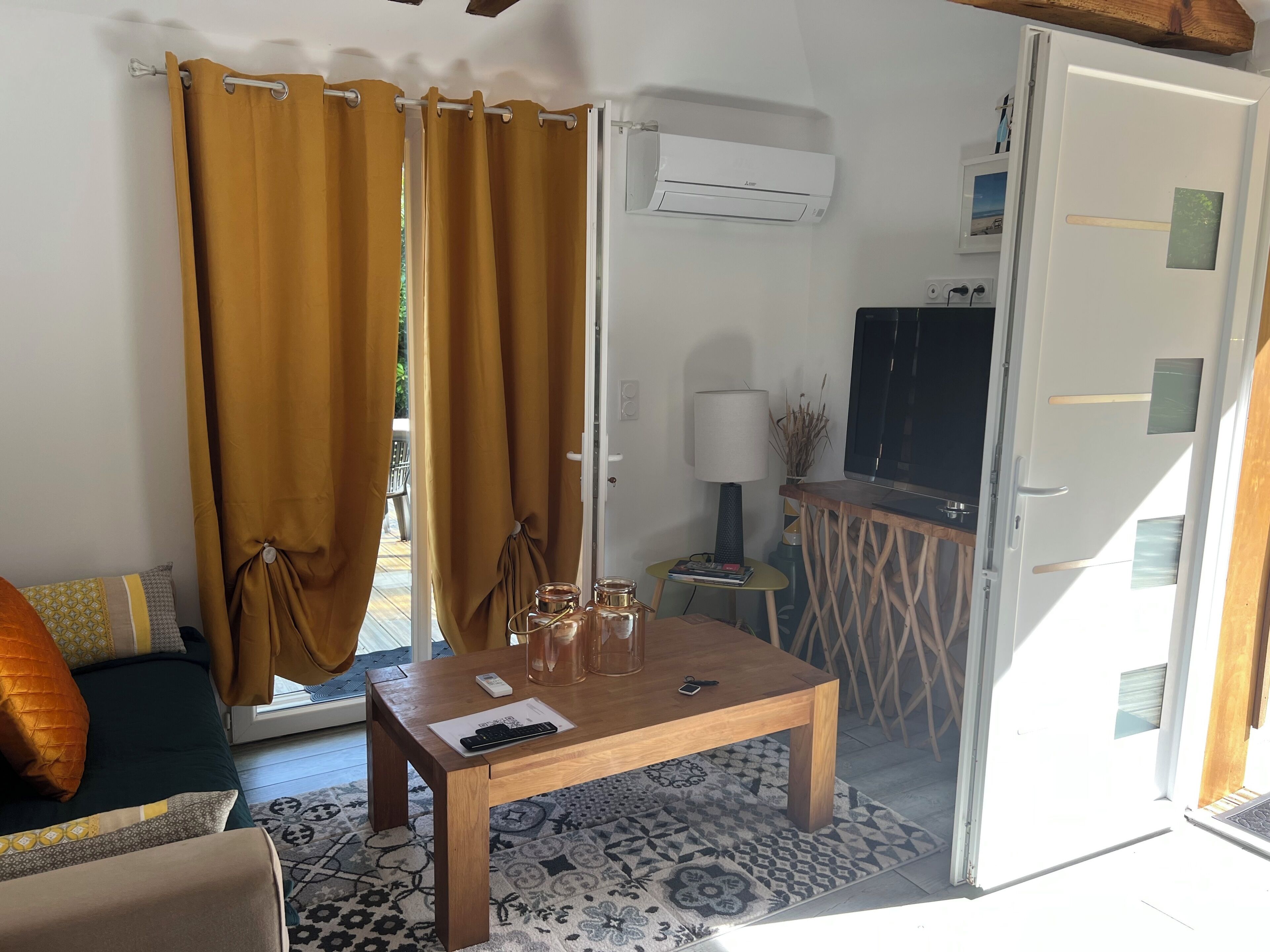 A room with a sofa, a coffee table, a lamp, and an air conditioning unit.