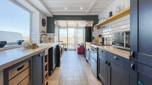 A modern kitchen with a large window, a built-in oven, and a microwave. - Harvest Moon - cottage close to harbour (Weymouth)