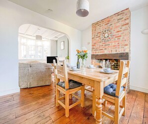Un comedor con chimenea de ladrillo, mesa de madera y sillas.