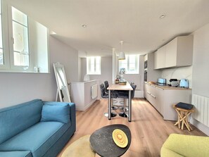 Cozy living space with a sofa against a window, dining area, and compact kitchen.