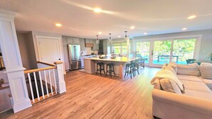 A spacious kitchen with a central island, wooden flooring, and a dining area with a view of the outdoors. - Newly remodeled, private Villa in Bolton Landing with all the comforts of home (Bolton)