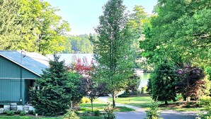 A residential area with a house, a driveway, and a lake in the background. - Newly remodeled, private Villa in Bolton Landing with all the comforts of home (Bolton)