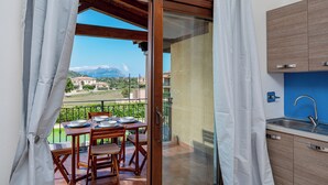 Ein Balkon mit Esstisch, Stühlen und Bergblick.
