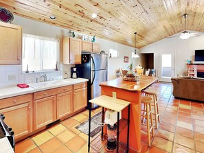 A spacious kitchen with wooden cabinets, a central island, and a dining area with a couch. - The Bungalow by Ruidoso Vacation Rentals (Ruidoso)