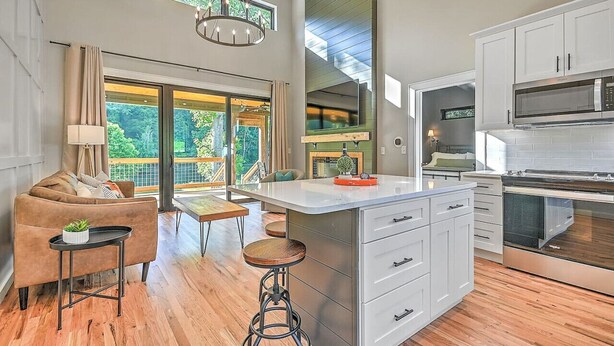 A modern kitchen with white cabinets, a large island, and a dining area with a sofa and bar stools.