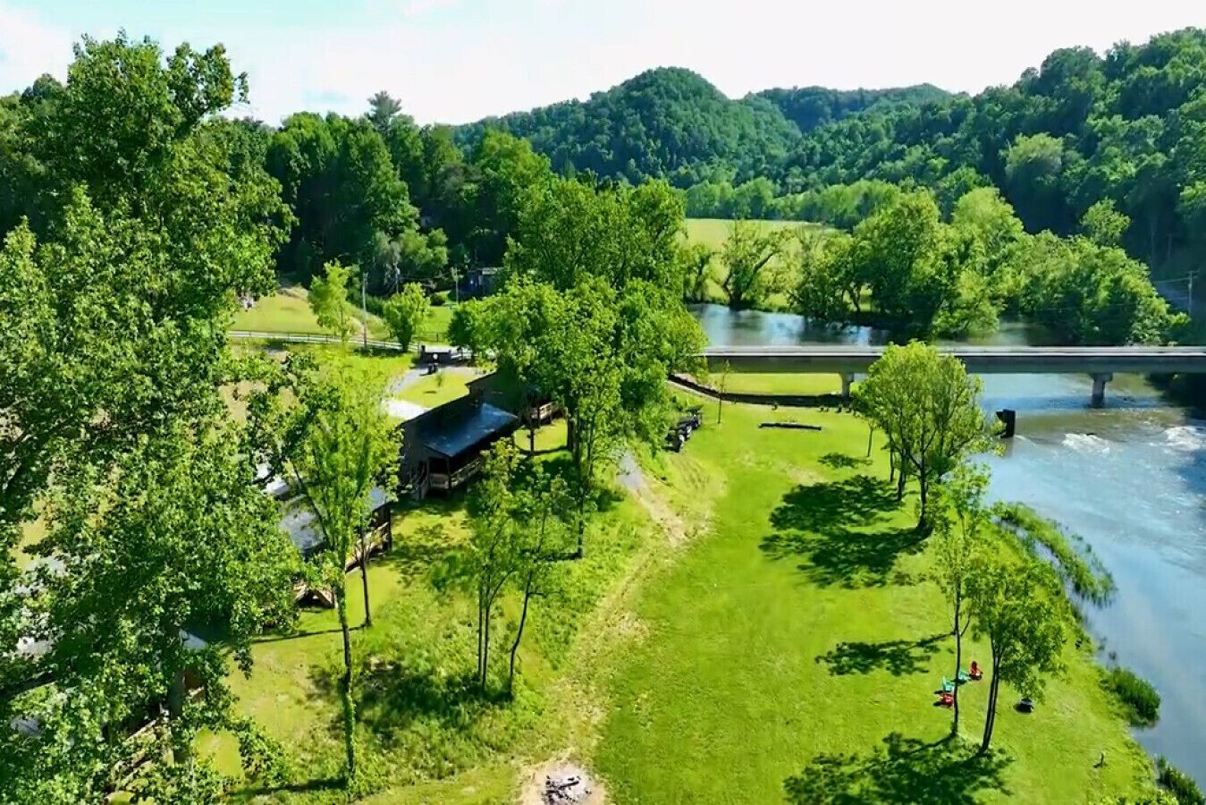 A riverside property with a covered outdoor area, a bridge, and lush greenery.