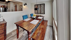 Ein Essbereich mit einem Holztisch, blauen Stühlen, einem Wanddekor und einem Spiegel.