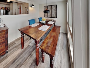 A dining area with a wooden table, blue chairs, a decorative wall piece, and a mirror. - Beachfront Bliss Bermuda by Ryson Vacation Rentals (Galveston)