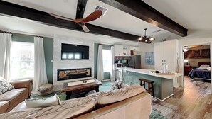 Ein modernes Wohnzimmer mit Kamin, einer Couch, einem Couchtisch und einer Küchenzeile mit Bar.