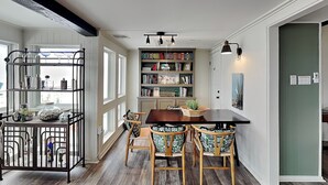 Ein Essbereich mit Holztisch und -stühlen, einem Bücherregal und einem Fenster mit Blick.