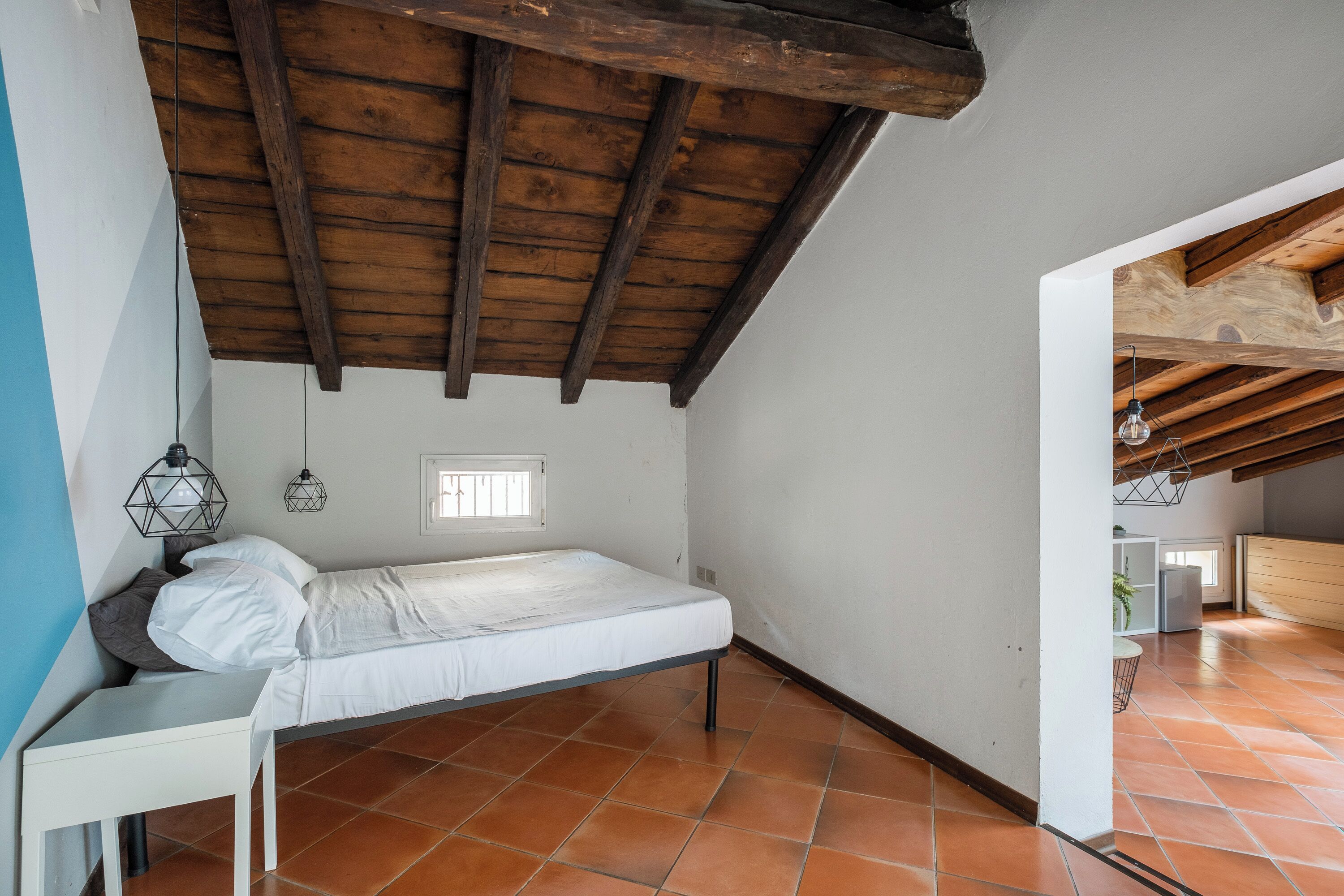 Ein Schlafzimmer mit Bett, Nachttisch und Fenster.