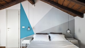Egy hálószoba, amelyben található egy ágy, két éjjeliszemélyzet, egy lámpás, egy ajtó és egy geometrikus mintázatú falfelület.