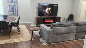 Ein Wohnzimmer mit Fernseher, Sofa und Kamin.