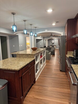 A modern kitchen with granite countertops, stainless steel appliances, and pendant lighting.