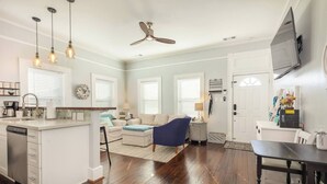 A spacious living area with a kitchen, dining table, and a ceiling fan.